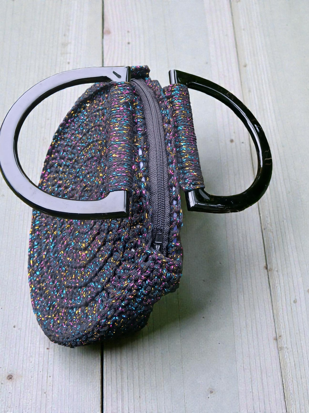 Détail du sac au crochet noir, montrant les reflets brillants et la texture artisanale.